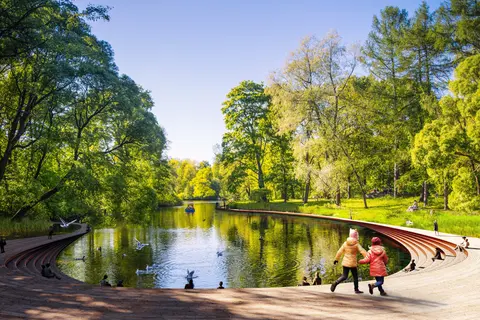 Lakeside boardwalk and terraced seating in the Aarhus Park Kongelunden vision, with children beside the water